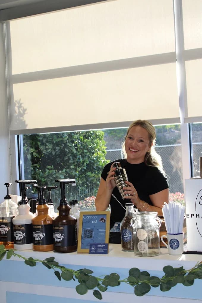 A smiling Cornerstone Coffee barista at an outdoor event coffee bar