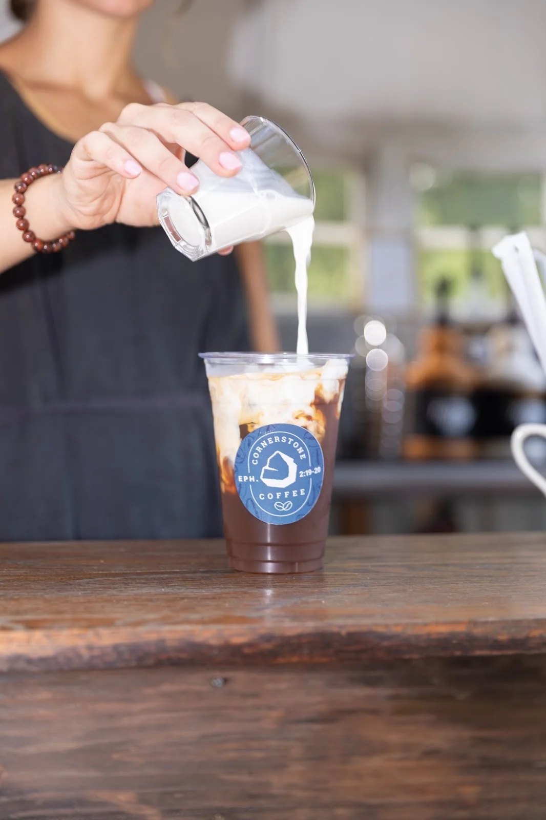 A Cornerstone Coffee barista pouring milk into an iced coffee at an event
