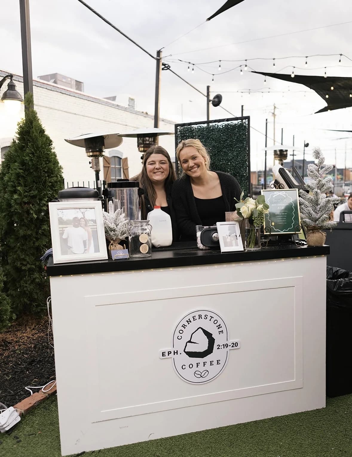 Two Cornerstone Coffee baristas behind the branded coffee cart at an outdoor evening event