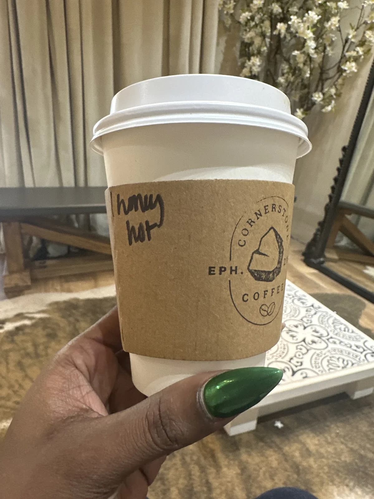 A branded Cornerstone Coffee hot cup held in hand at an event