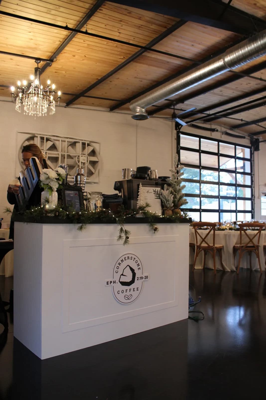 The Cornerstone Coffee cart set up beneath chandeliers at an indoor wedding venue
