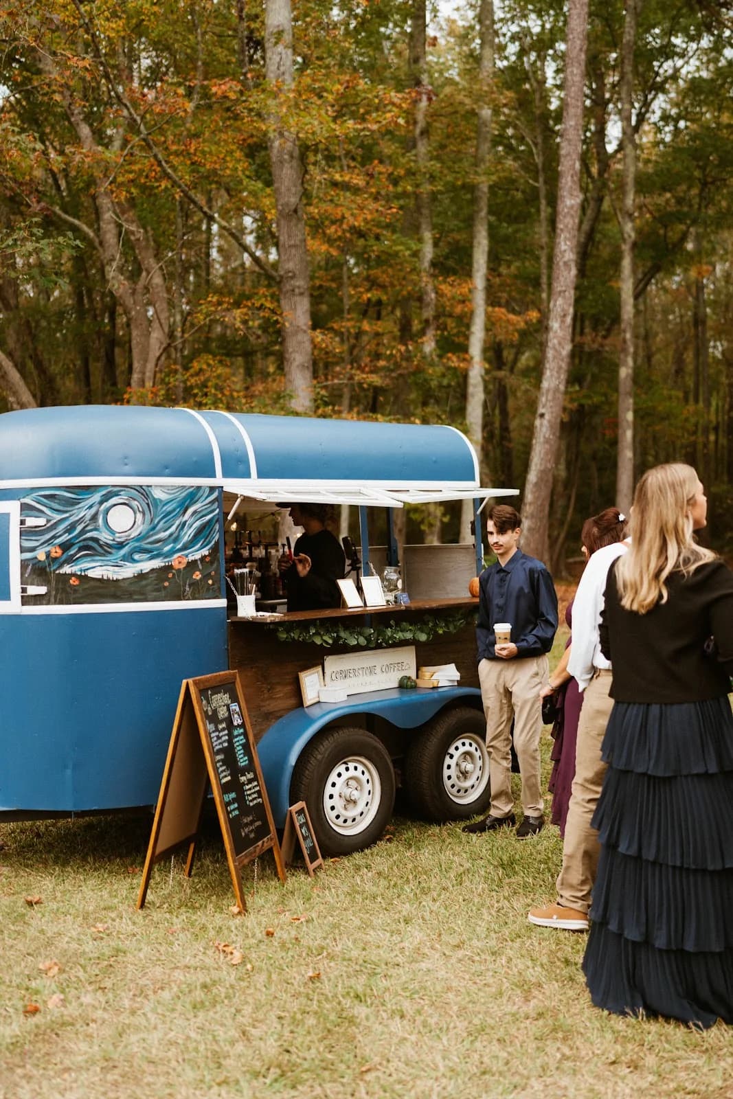 Guests collecting drinks at Cornerstone Coffee's mobile trailer at an autumn outdoor event