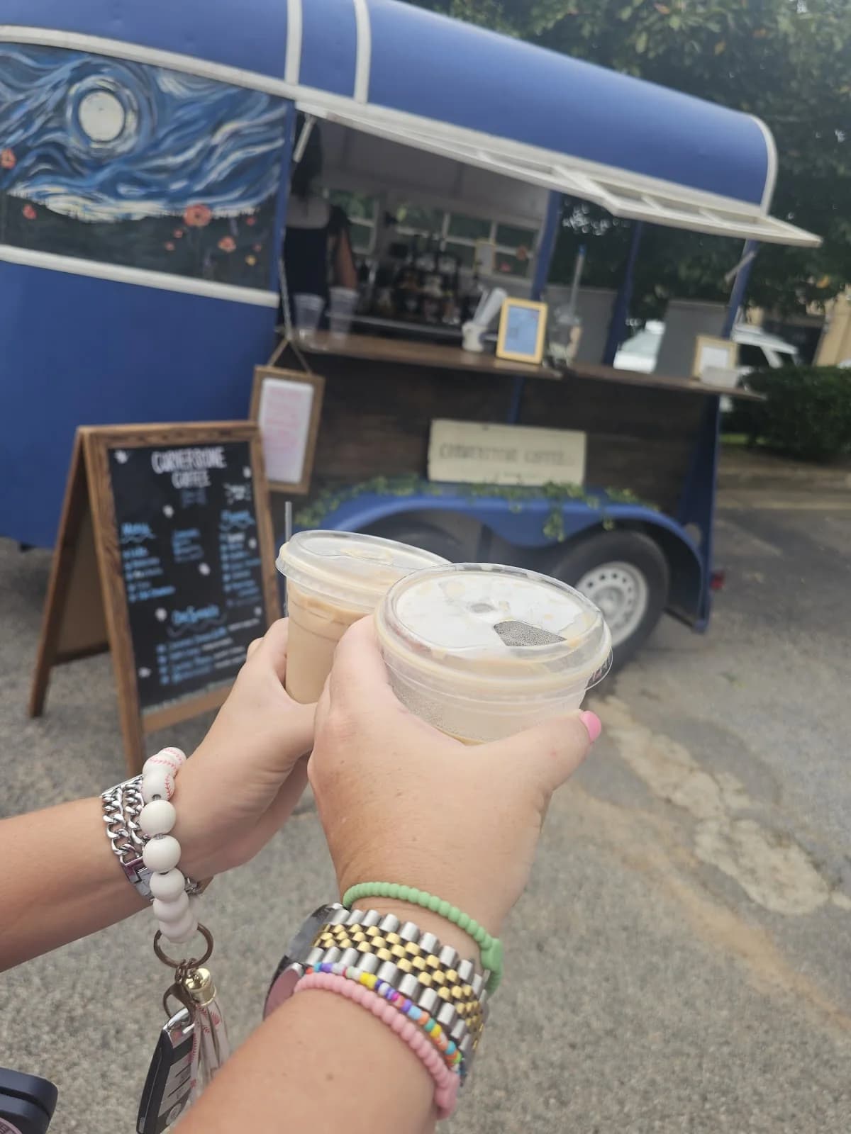 A guest holding a Cornerstone Coffee cup beside the mobile coffee trailer