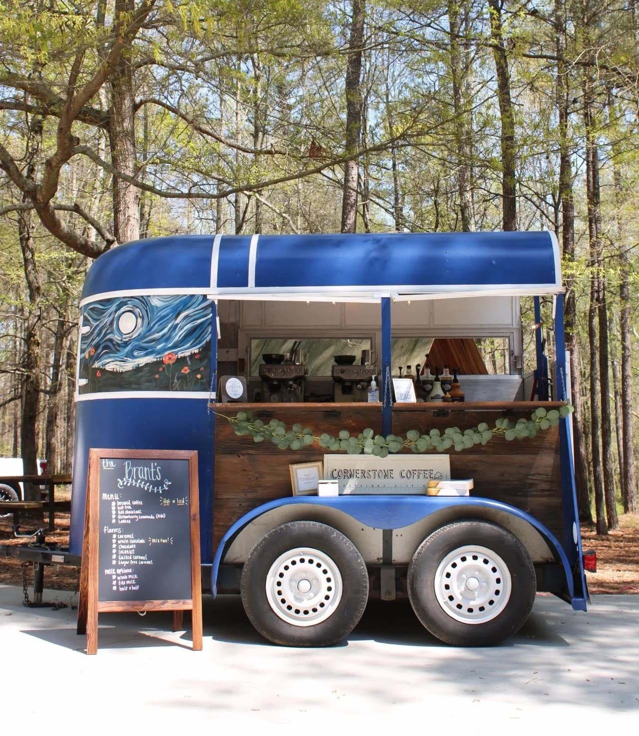 Cornerstone Coffee's navy mobile coffee trailer with its hand-painted starry mural, set up at a wooded Georgia wedding venue