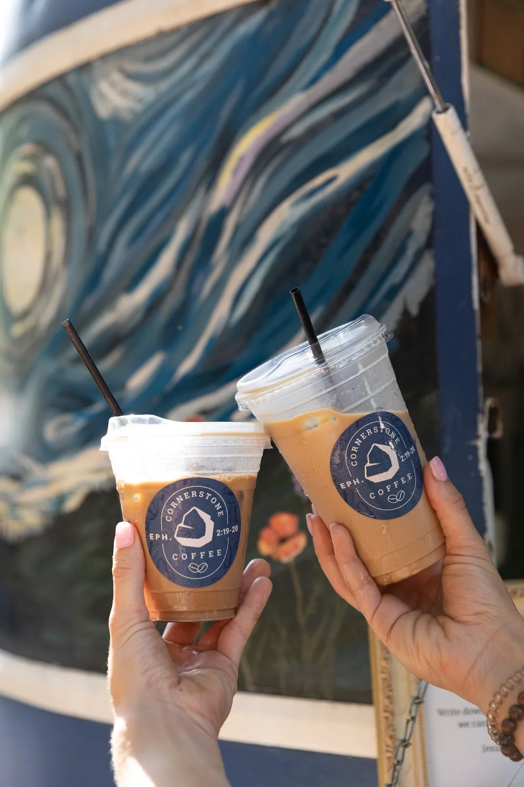 Two Cornerstone Coffee iced drinks held up in front of the trailer's starry mural
